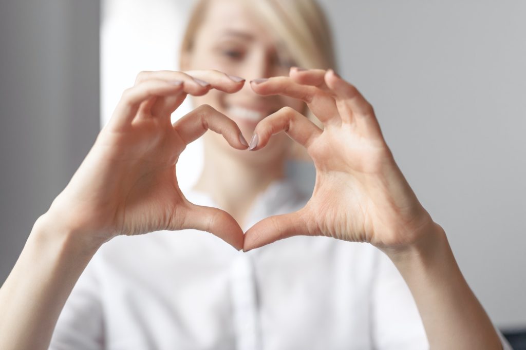 Blurred lady showing hand heart gesture