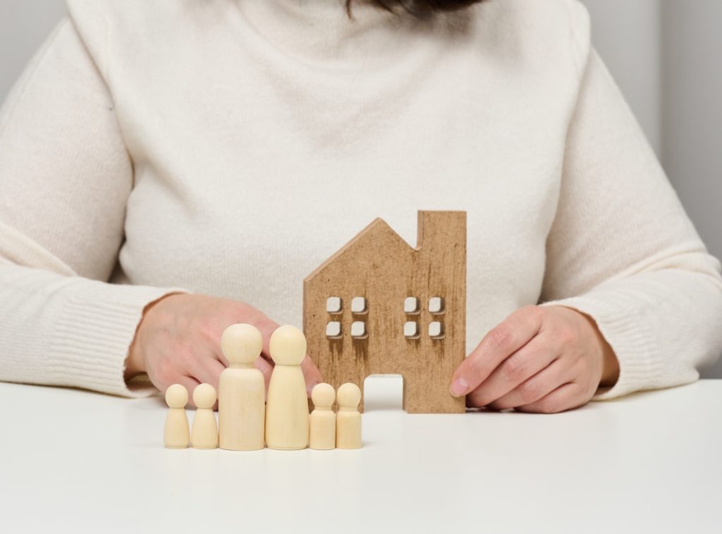 Wooden house and figures of a family. Real estate insurance concept, happy family